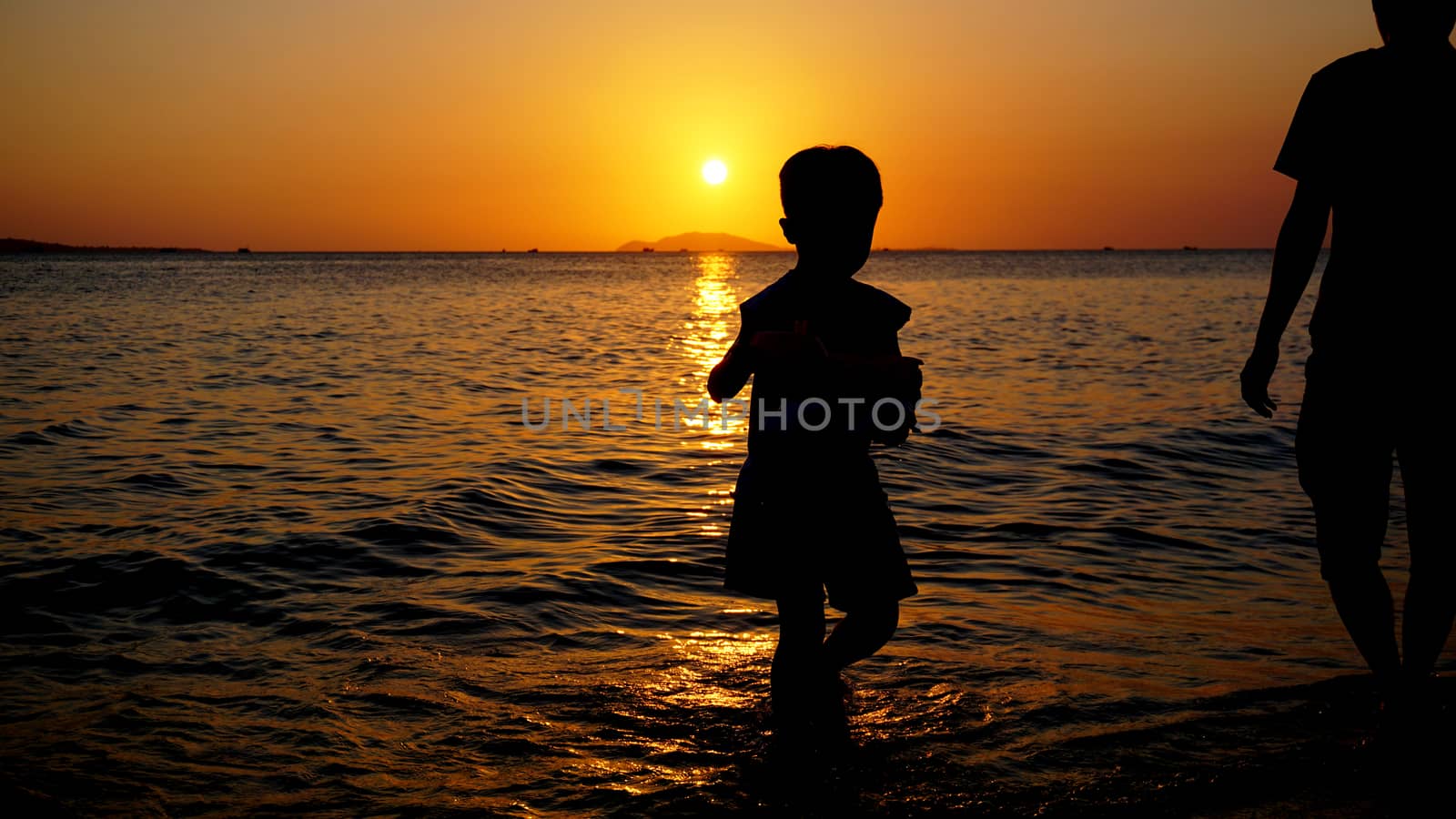 Father and child playing on the beach at the sunset time. Concept of friendly family.