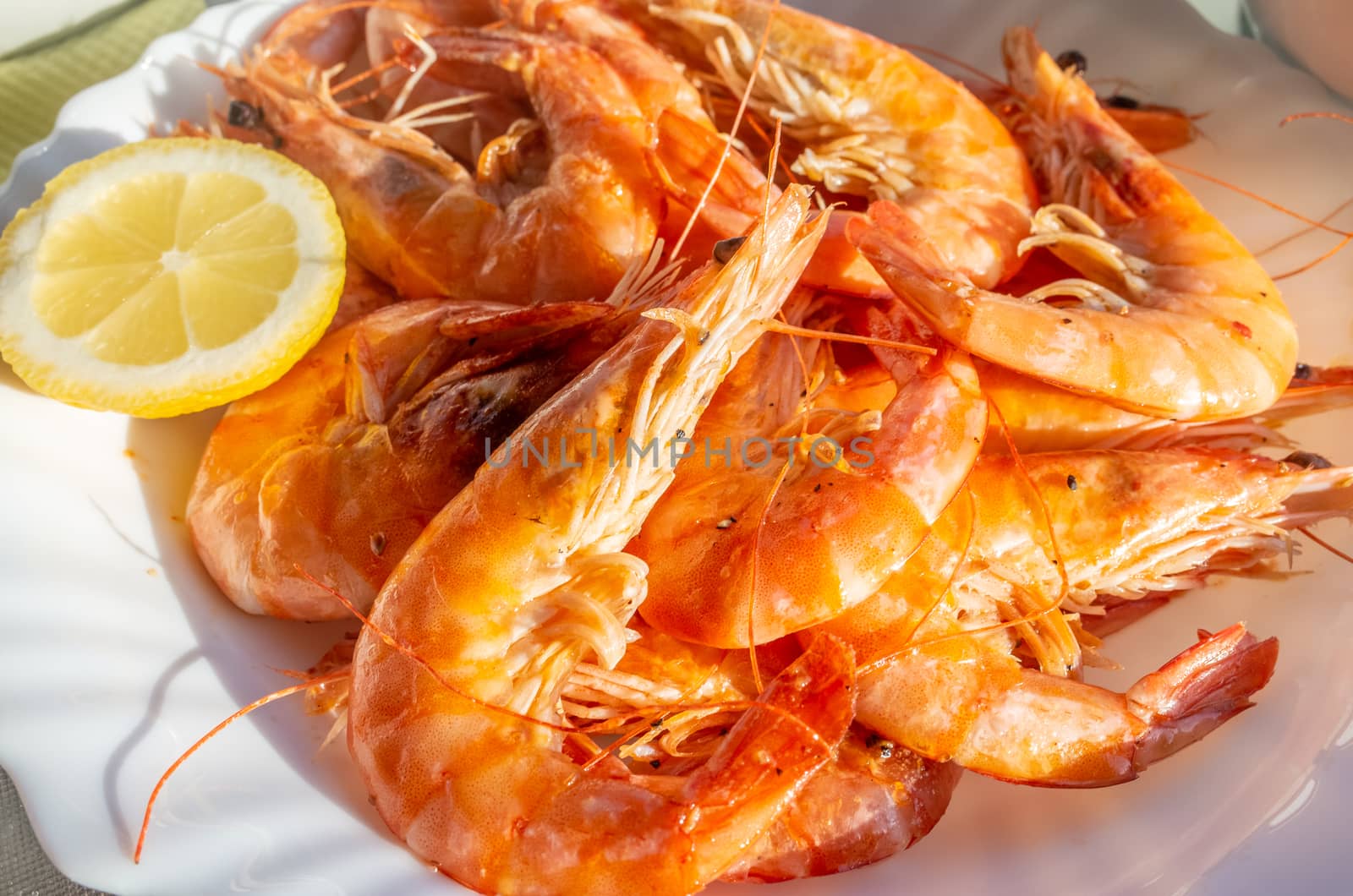 A plate of fried fresh king prawns with a slice of lemon.