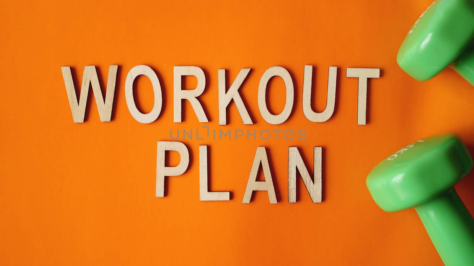 Fitness concept, workout plan. Green dumbbells on orange background. Top view by natali_brill