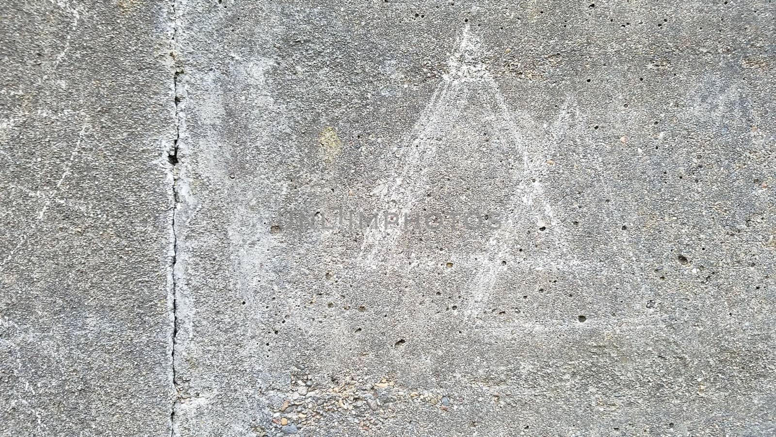 grey cement wall with two triangles scratched or drawn on the surface