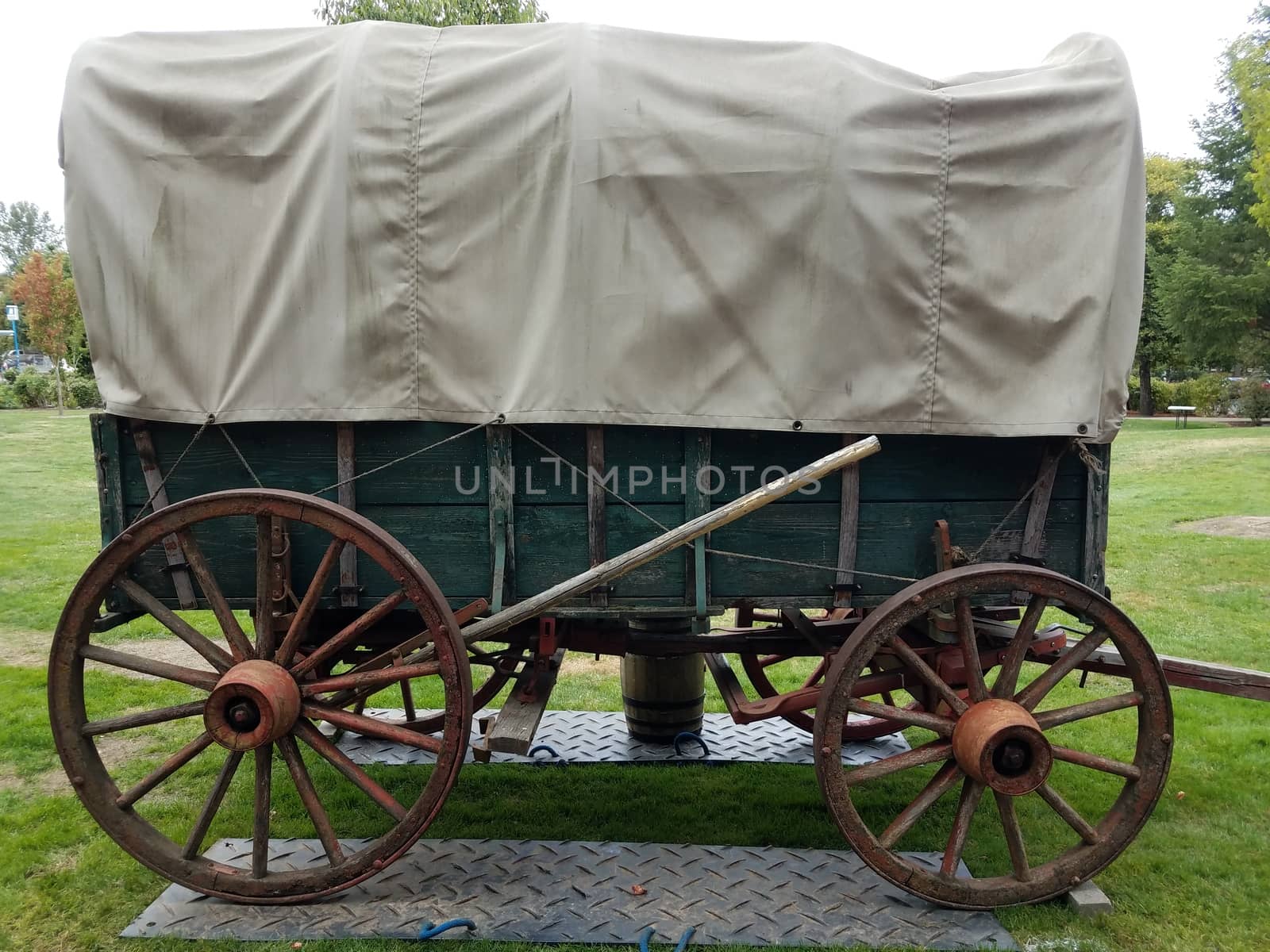green and brown stagecoach or wagon on metal plates and grass