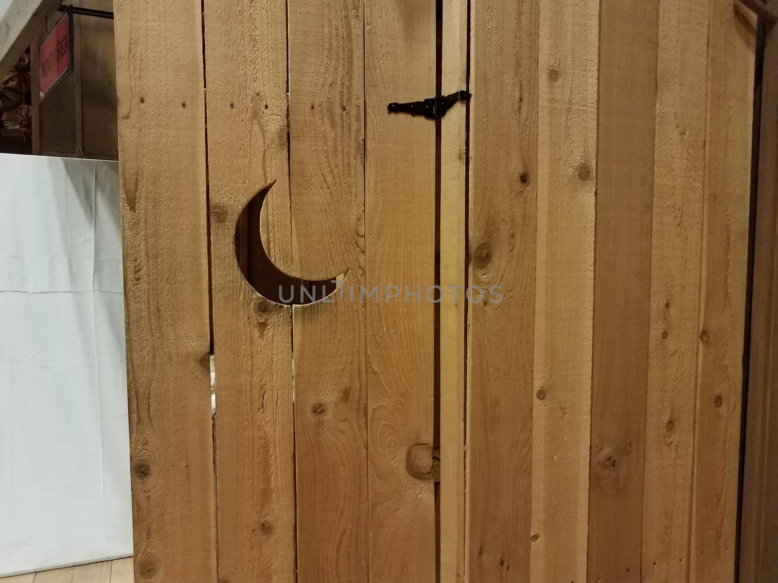 brown wooden door to outhouse bathroom with moon shaped hole or window