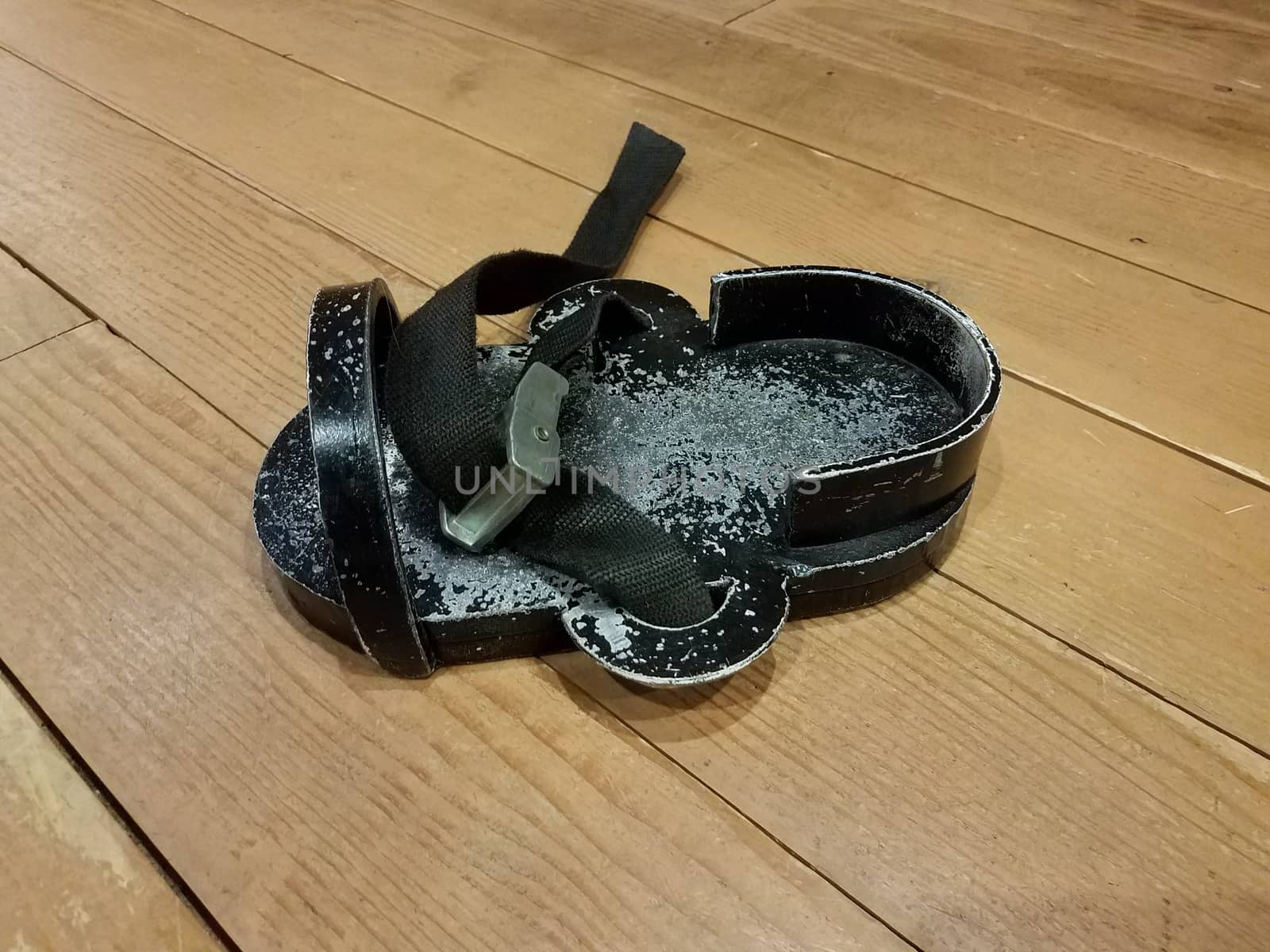black metal weighted shoe or sandal on brown wood floor