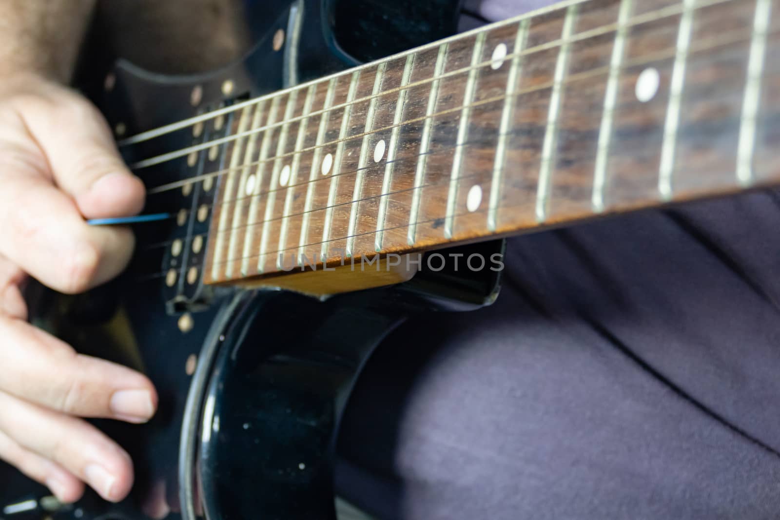 Close-up of man playing lead guitar solo on black guitar