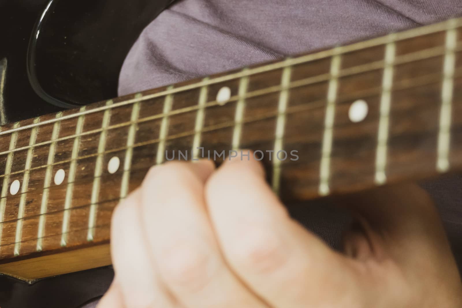 Close-up of man playing lead guitar solo on black guitar