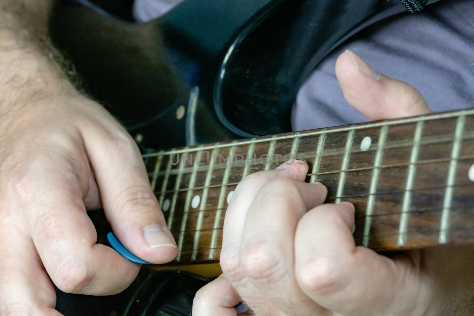 Close-up of man playing lead guitar solo on black guitar