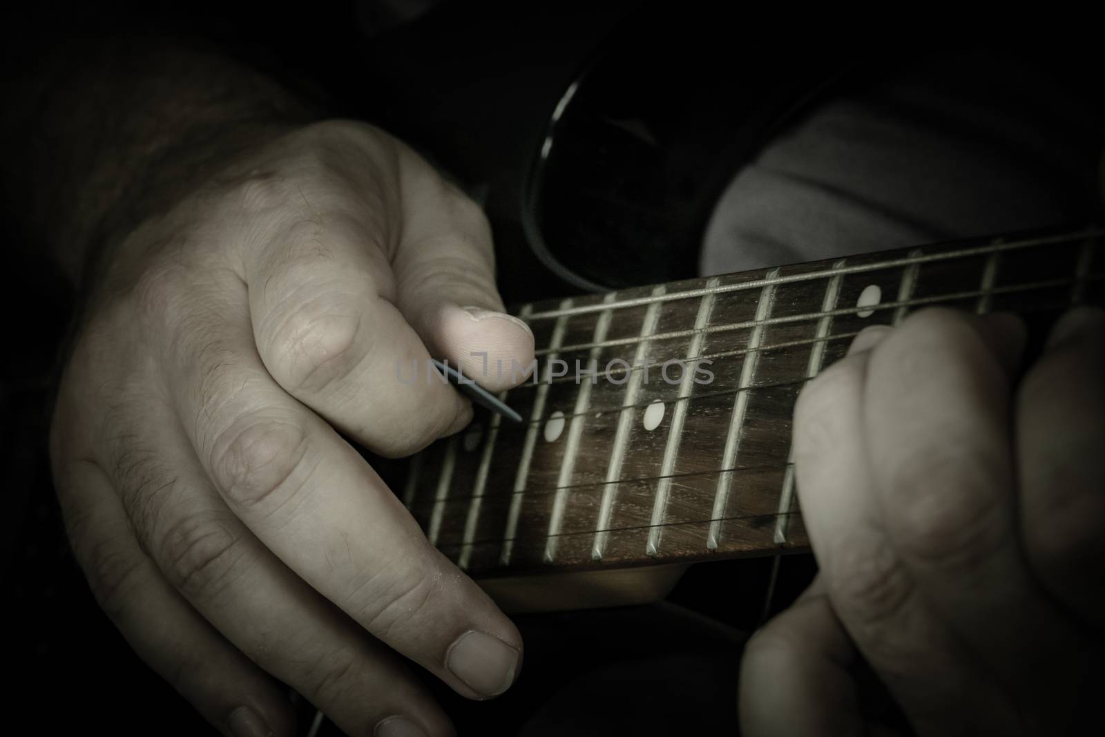 Close-up of man playing lead guitar solo on black guitar