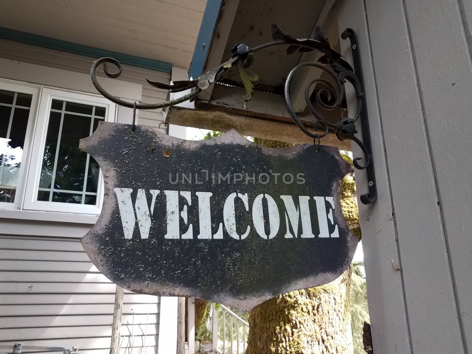 weathered black metal welcome sign hanging on wall by stockphotofan1