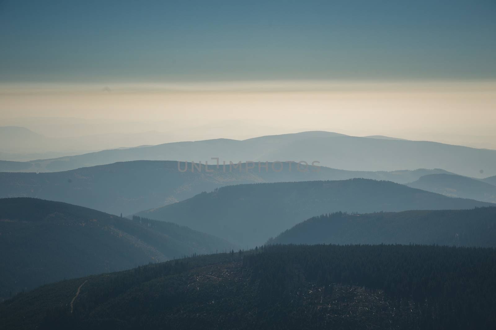 Distant mountain range and thin layer of clouds on the valleys in the autumn evening.