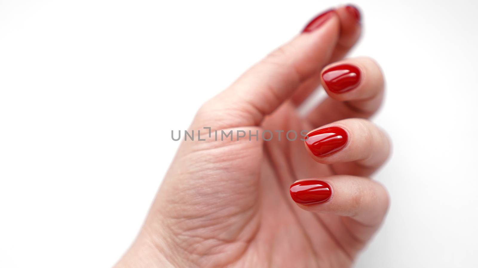 Beautiful female hand with fresh red manicure and nail isolated on white background