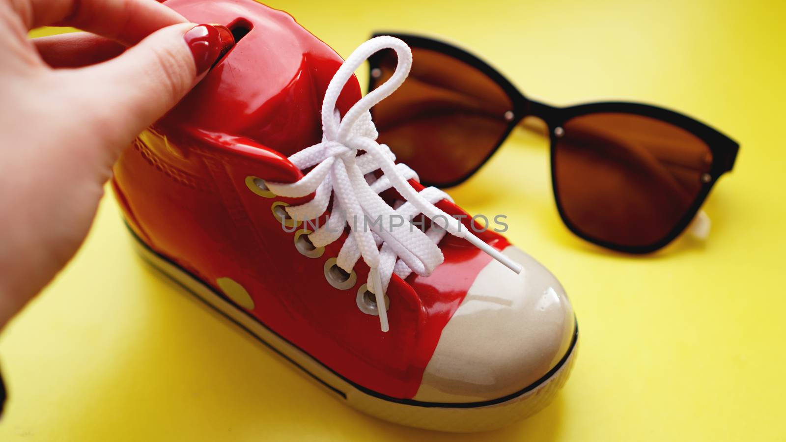 Moneybox in the form of sneakers. Sunglasses on a yellow background by natali_brill