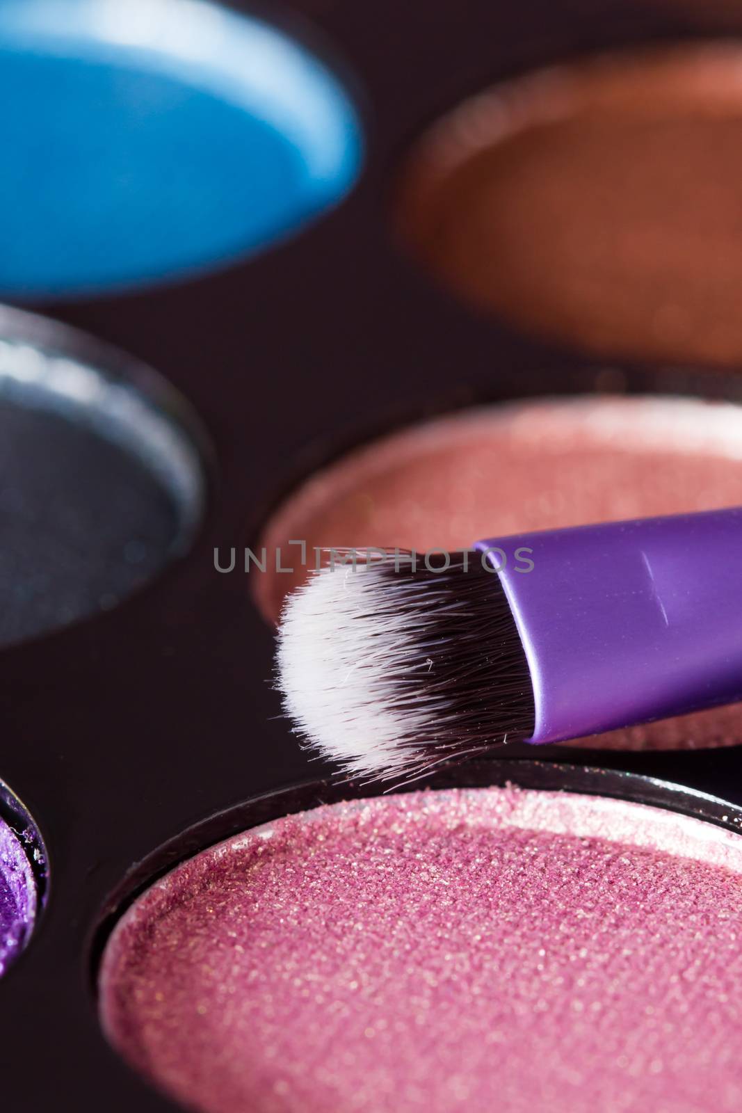 Snytethic makeup brush with colorful makeup palette in the background