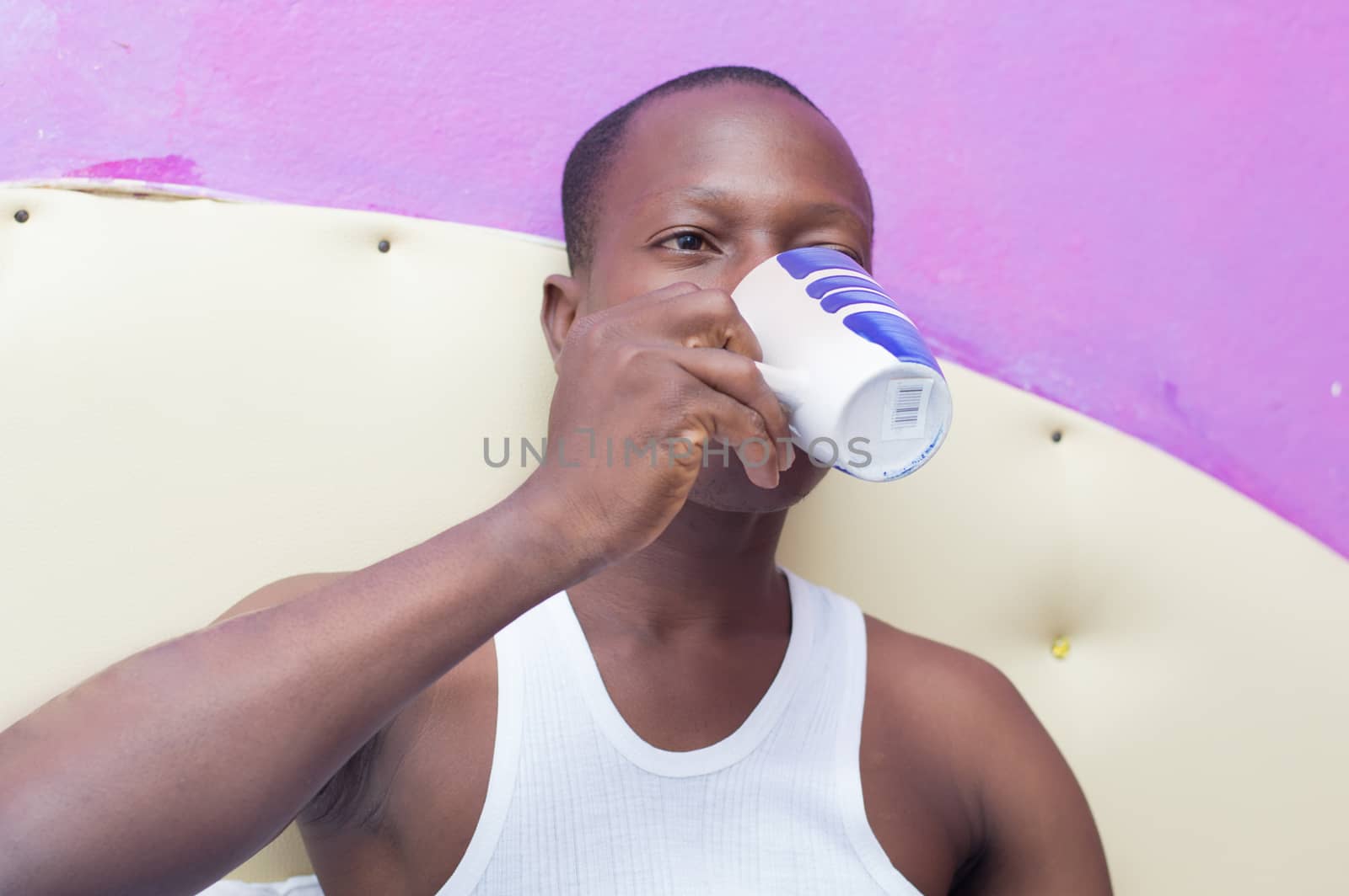 This young man lying in bed drinking coffee