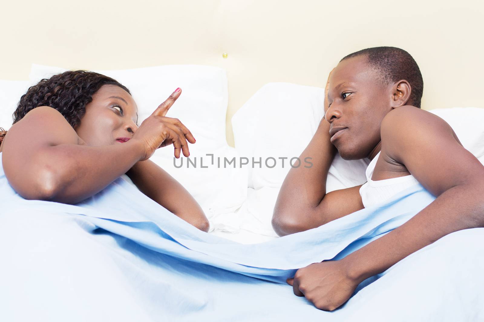 these young people lying face to face in the bed talking with pleasure.