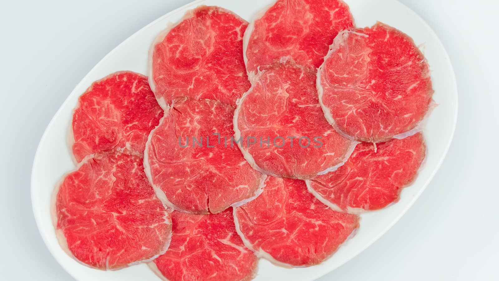 Top view of some raw beef on a plate over white background