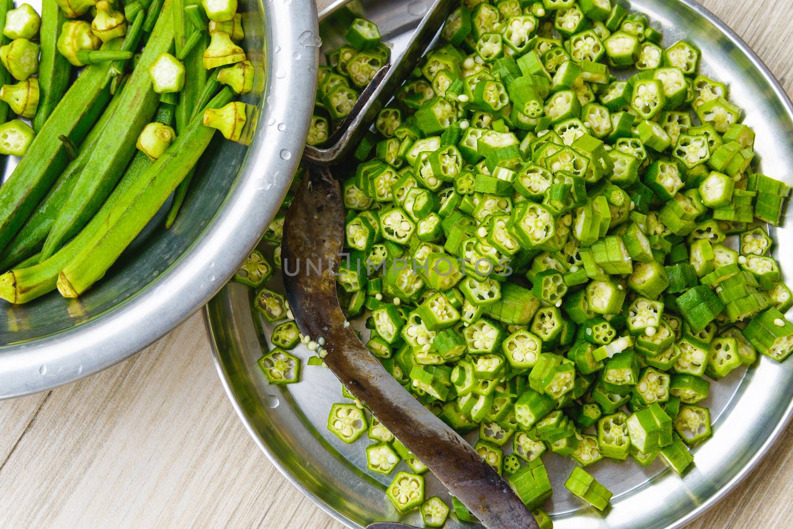 Overhead shot of okras and cut okras. A traditional nepalese knifein the plate.