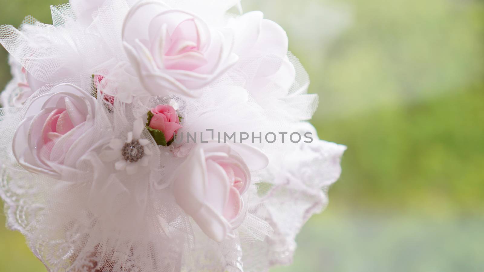 Wedding bouquet made of white roses on a blurred green background