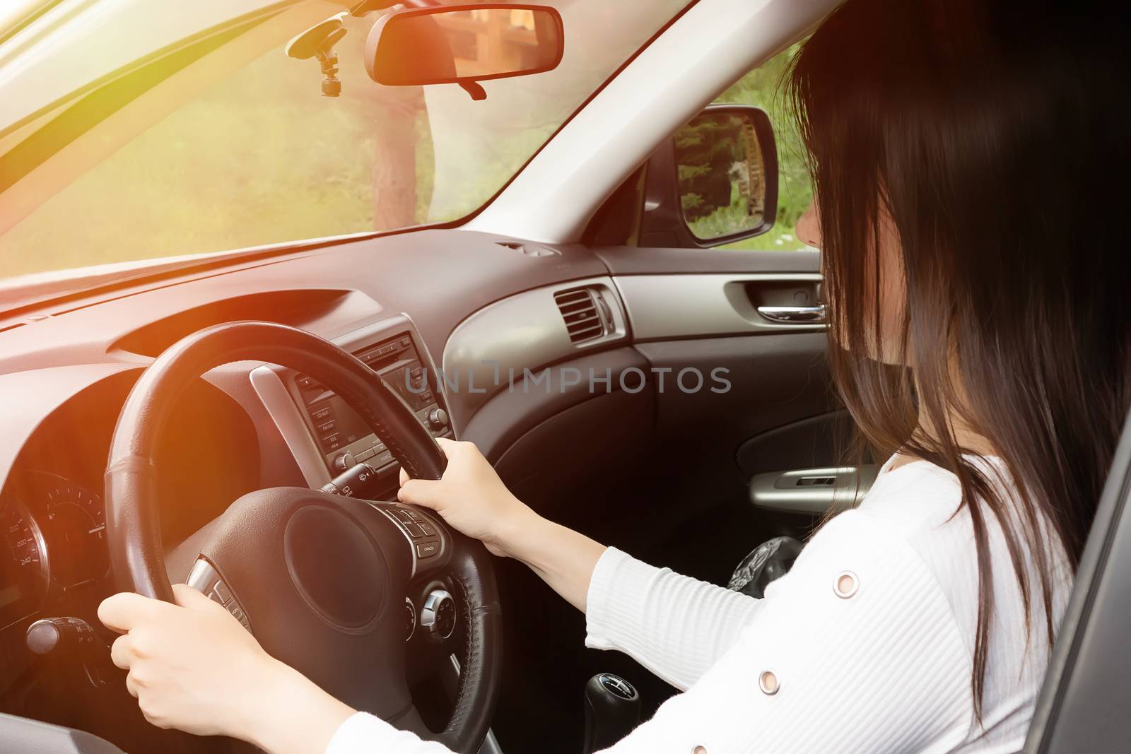 Young girl with long dark hair driving a car.