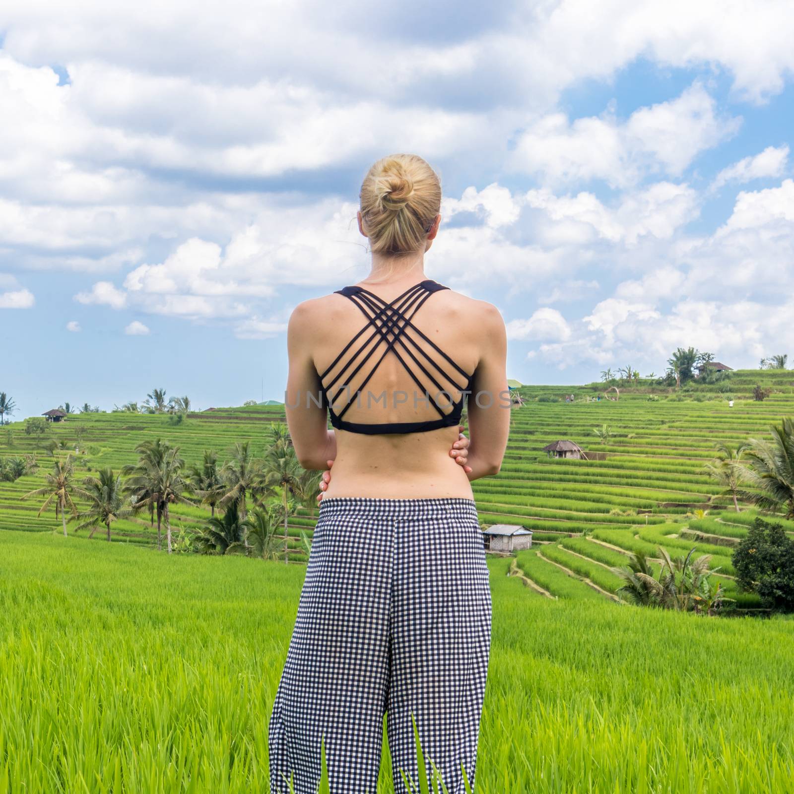 Relaxed sporty female traveler enjoying pure nature at beautiful Jatiluwih rice fields on Bali. Concept of sustainable tourism, nature enjoyment, balanced life, freedom, vacations and well being.