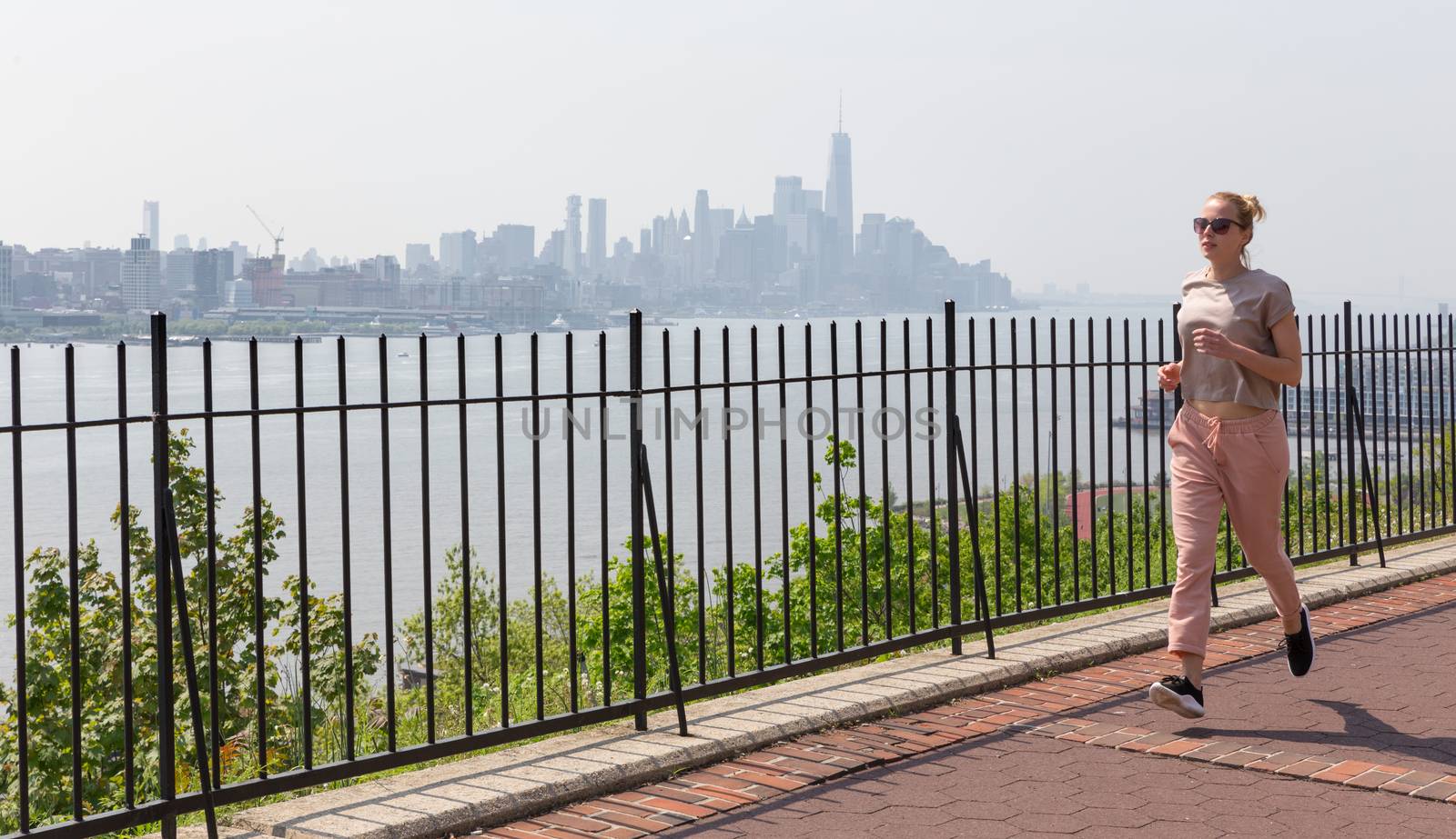 Healthy lifestyle. Woman is running on Hamilton ave by Hamilton park, New Jersey. Manhattan of New York City in the background.