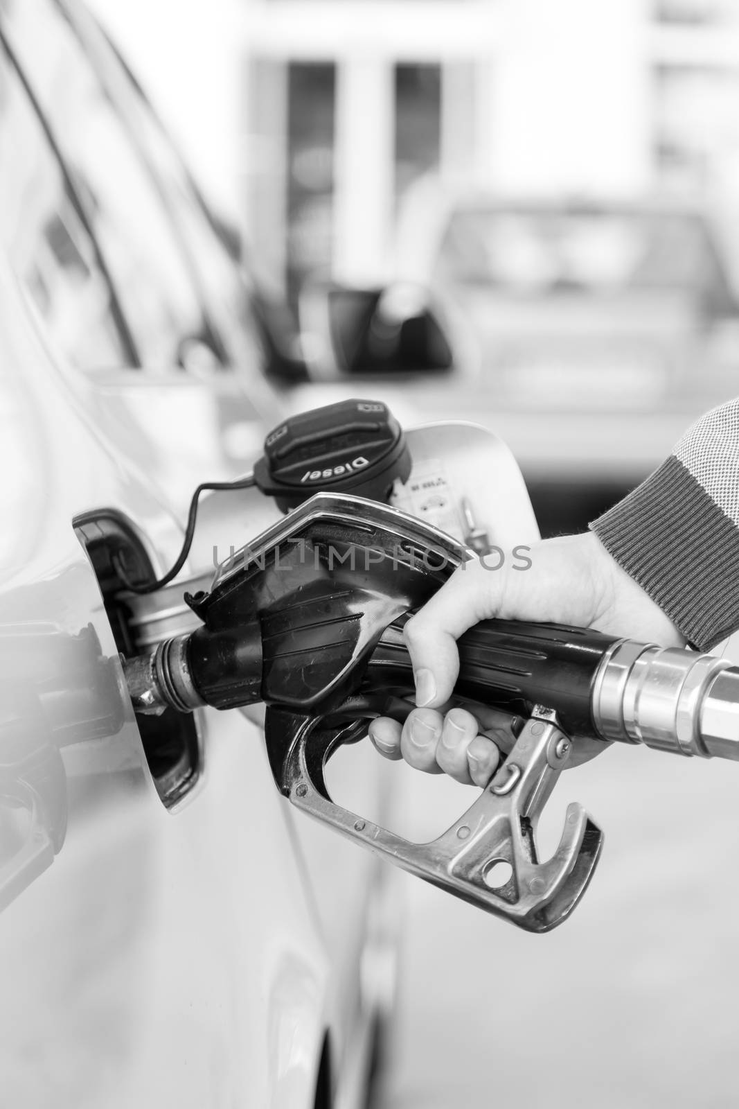 Closeup of mans hand pumping gasoline fuel in car at gas station. by kasto