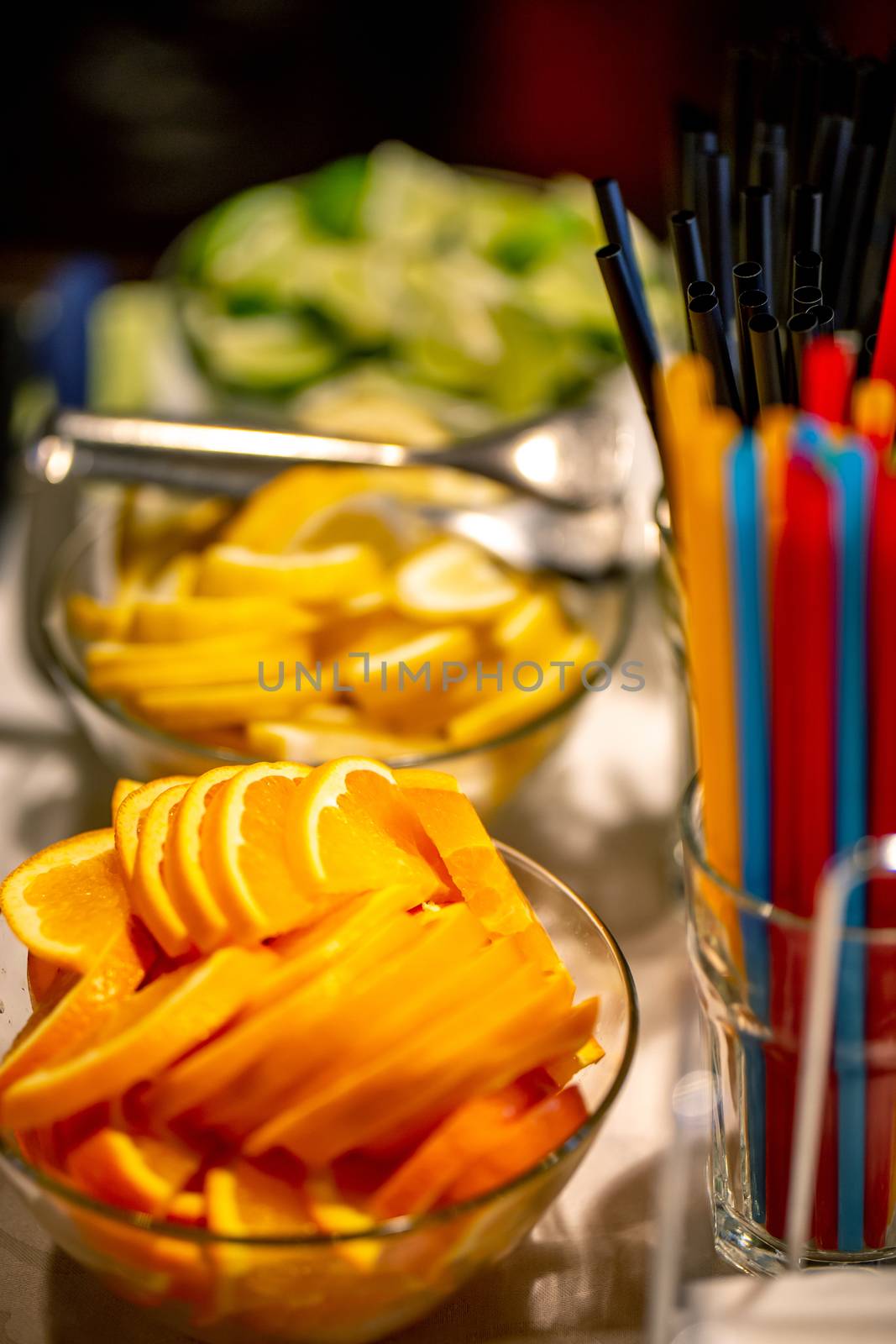 Orange, lemon and lime slices arranged on the glass bowl setting on holiday table. Focus on orange slices.