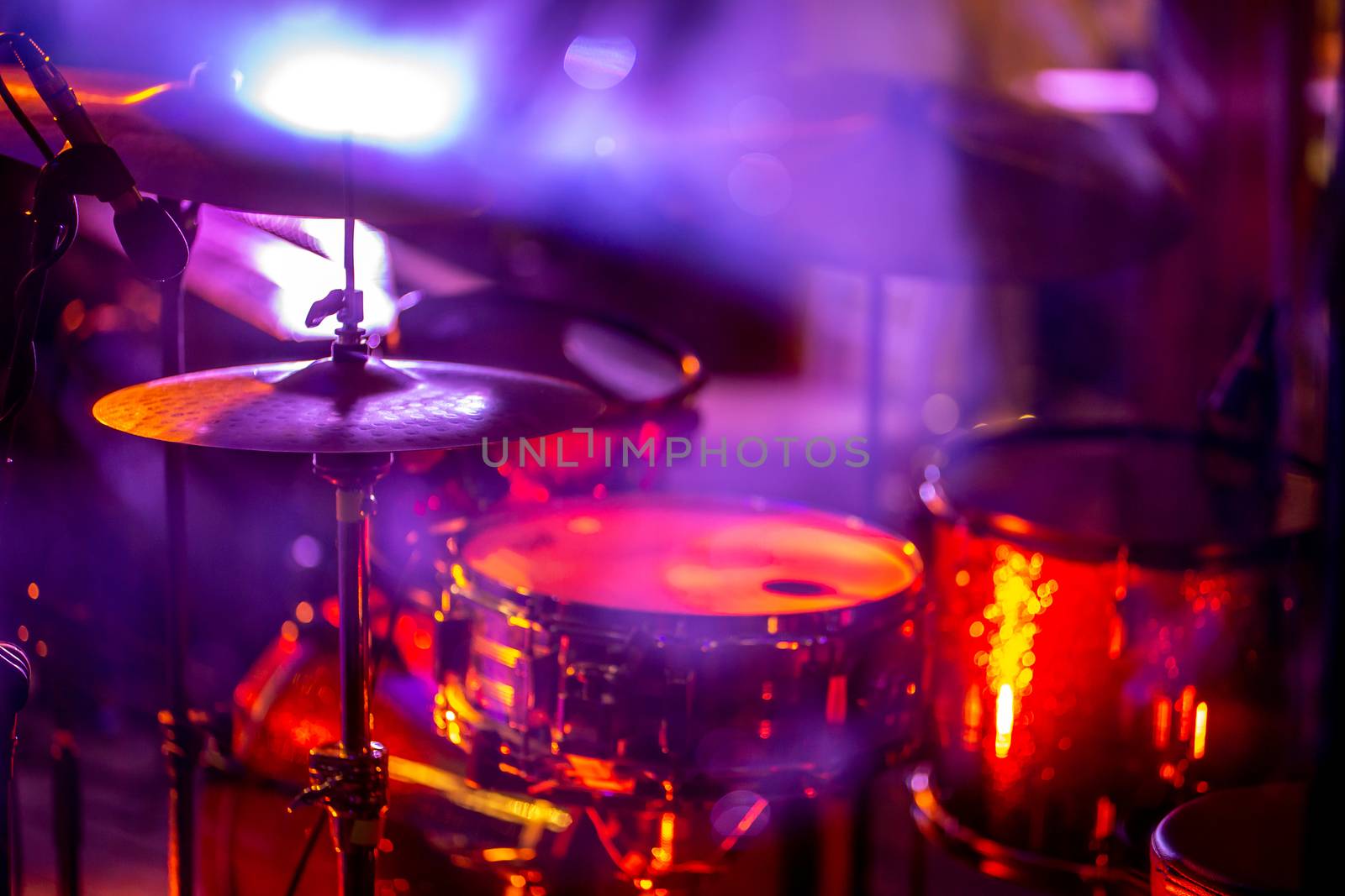 Empty abstract light illuminated stage with drumkit and microphone. Drums in multicolored light during celebrations on stage.