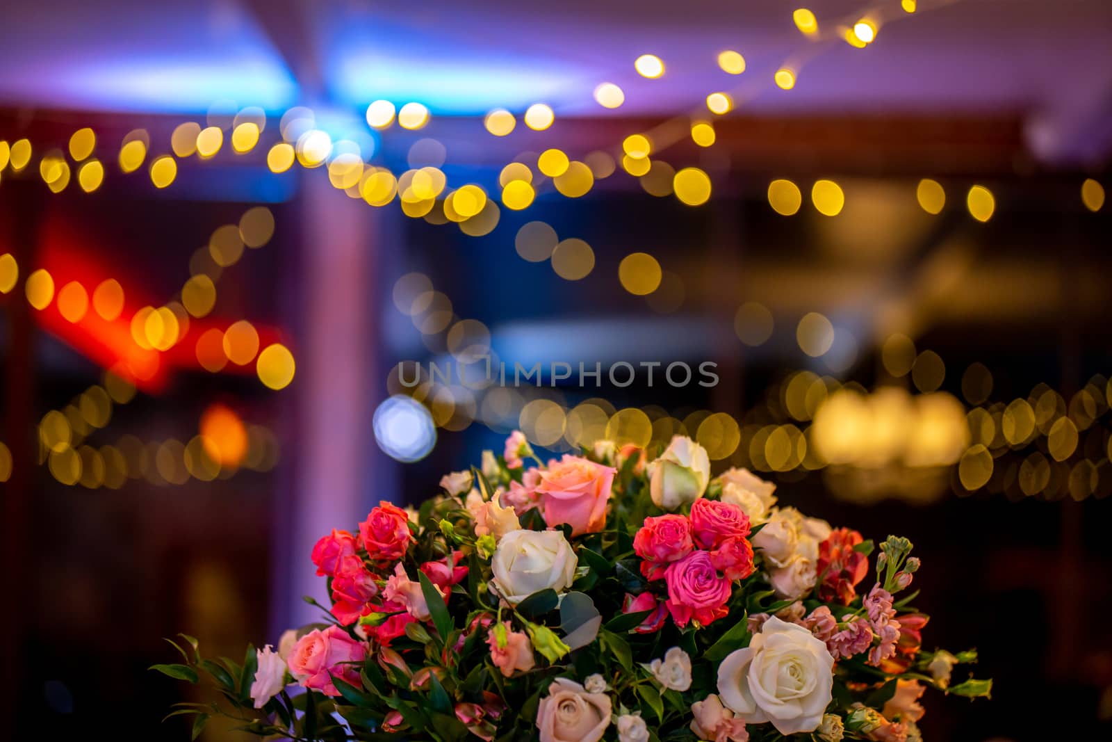 Bouquet of flowers on background of colorful bokeh light. Closeup of wedding flowers bouquet and blurred colorful lights in back.