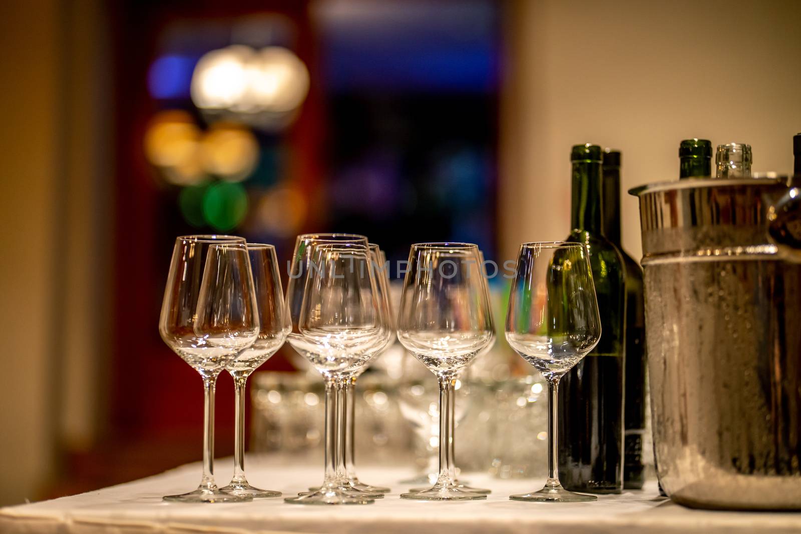 Empty glasses, wine bottles and bucket with ice on table in restaurant. Ice bucket, wine glasses and bottles arranged on the table for wedding reception.