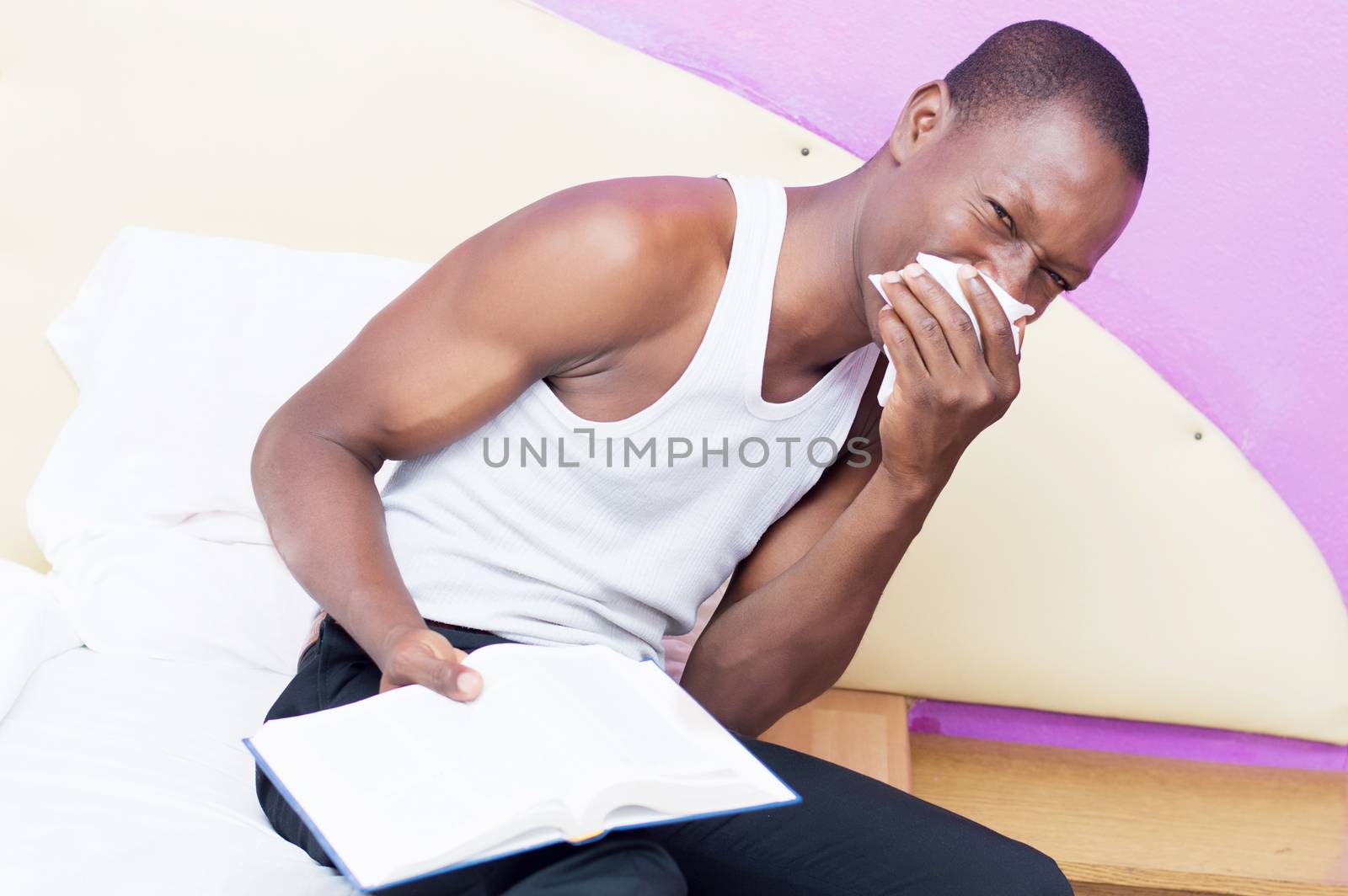 this young man is lying on his bed with a book in hand and trying to sleep