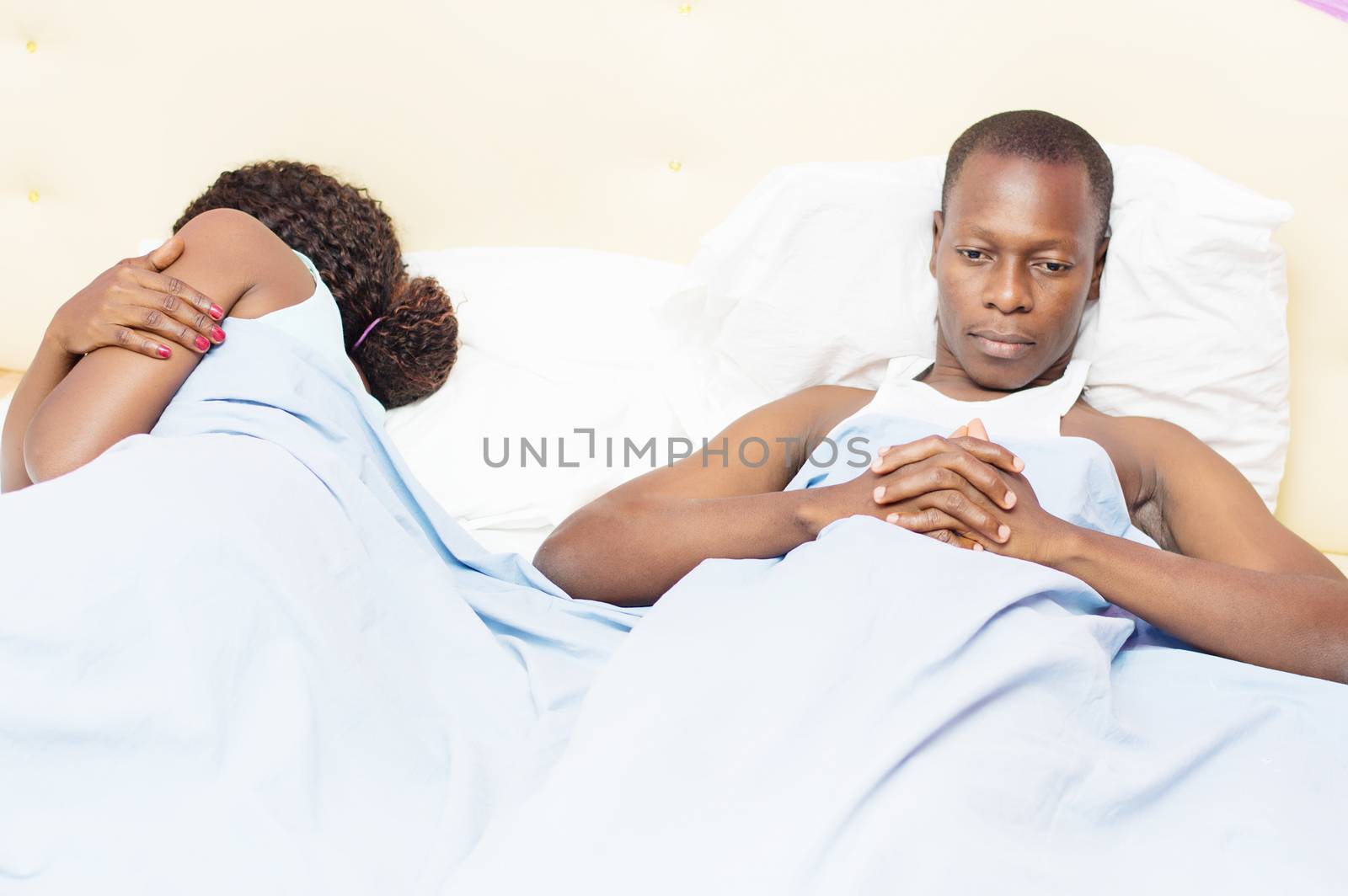 This young man lying in bed with his wife, is thoughtfully after a domestic dispute