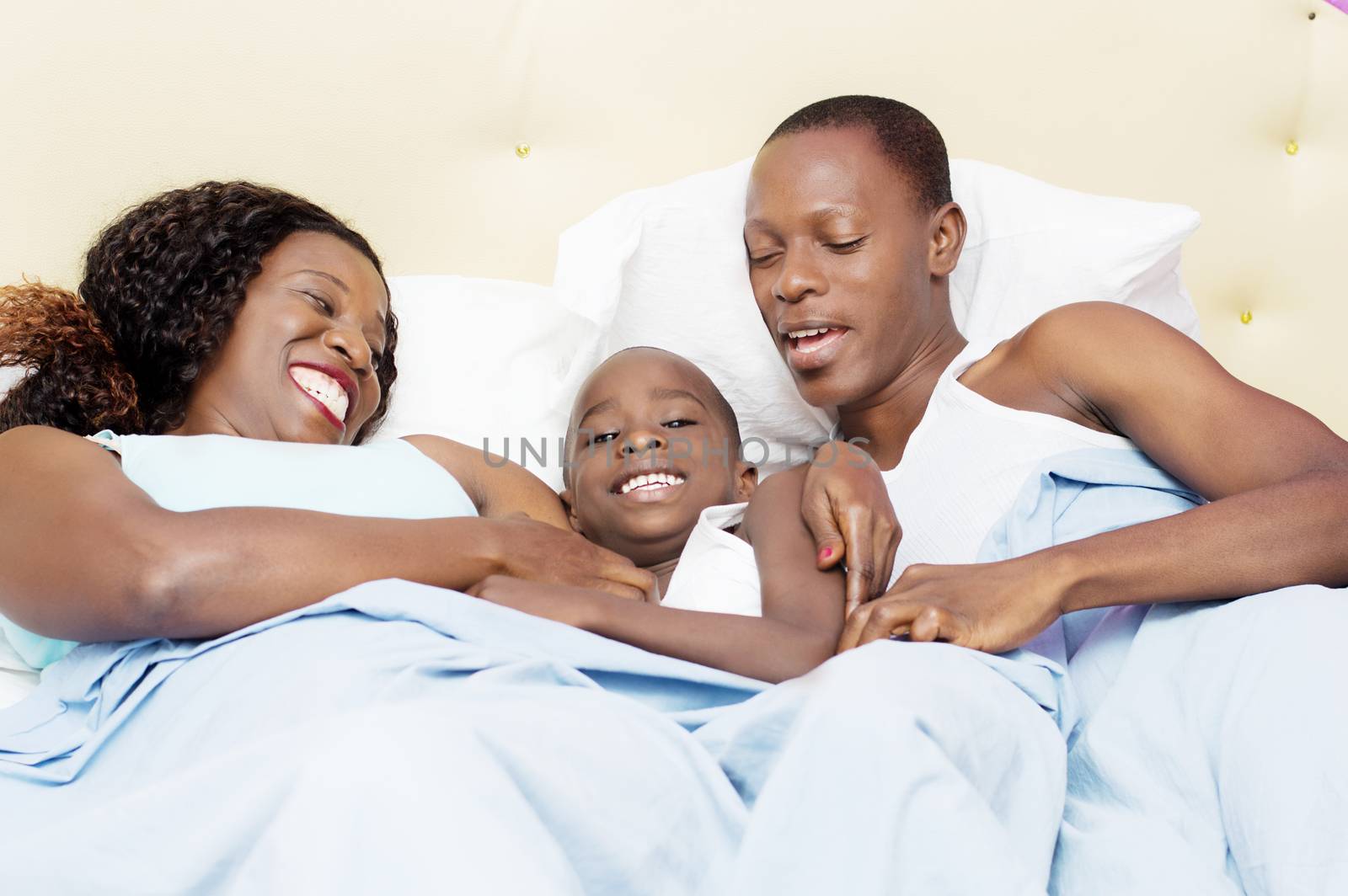 family lying in bed is happy to share good holiday together