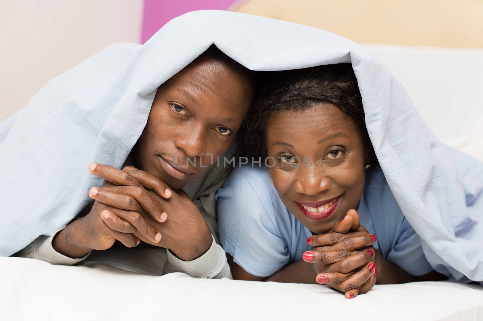 this young couple looks at the camera, smiling under their coverage.