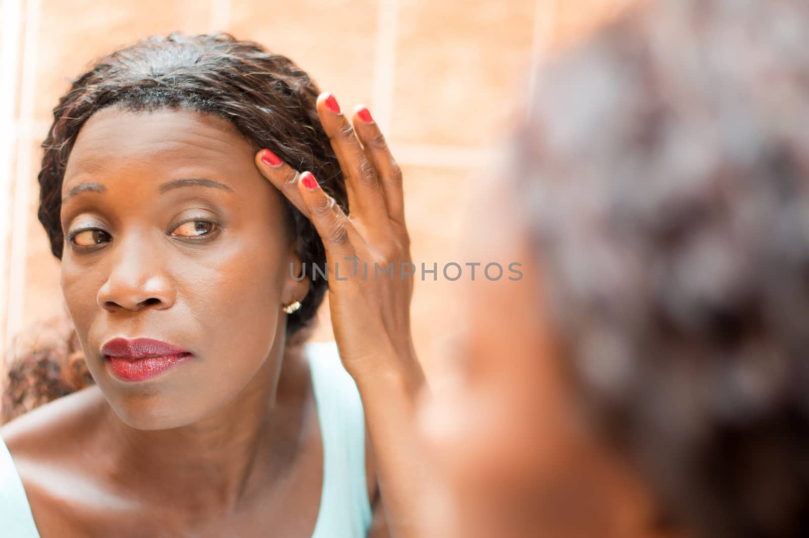 young woman looks in the mirror in order to properly apply makeup.