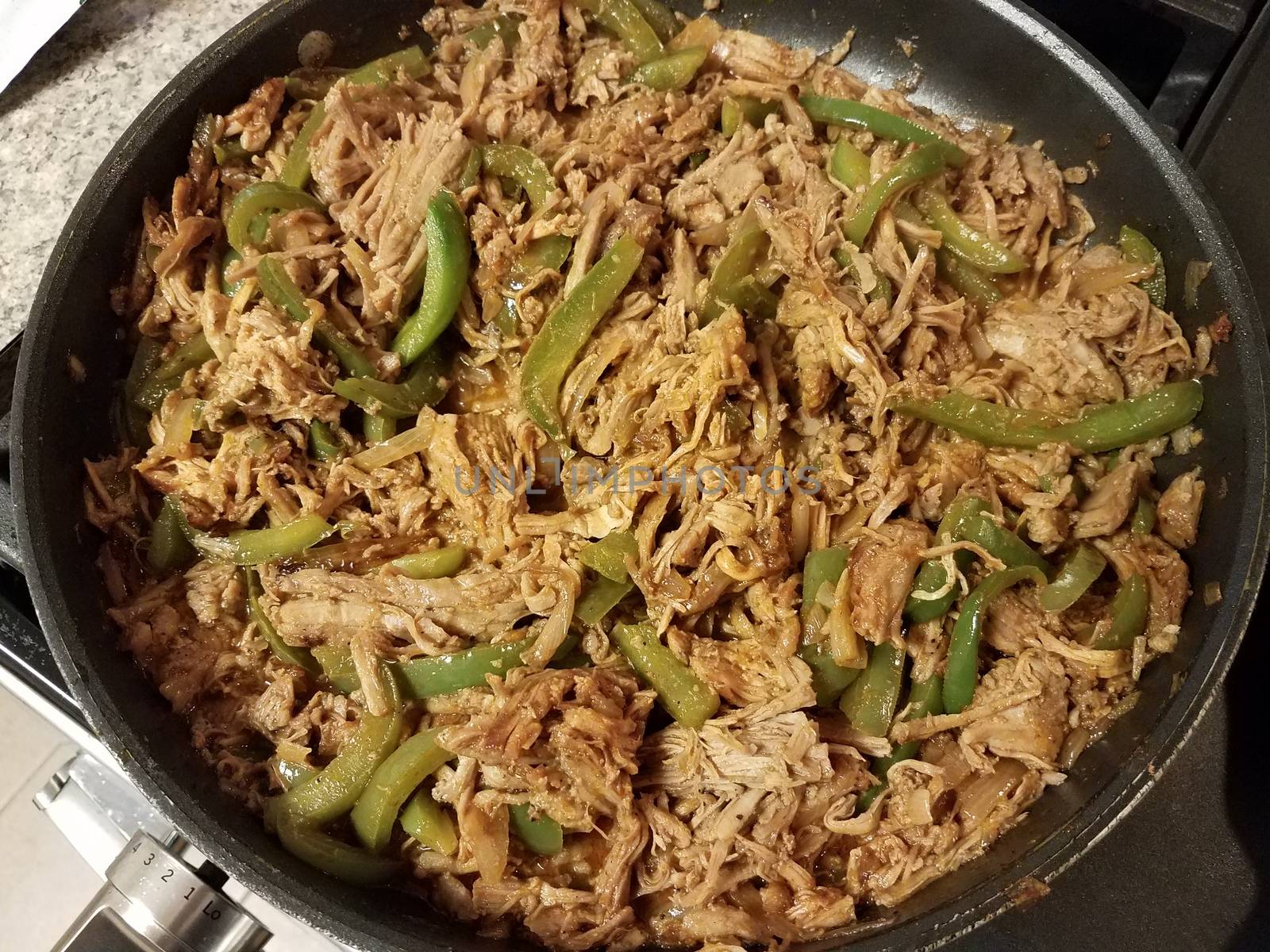 frying pan with pulled pork and green peppers on stove