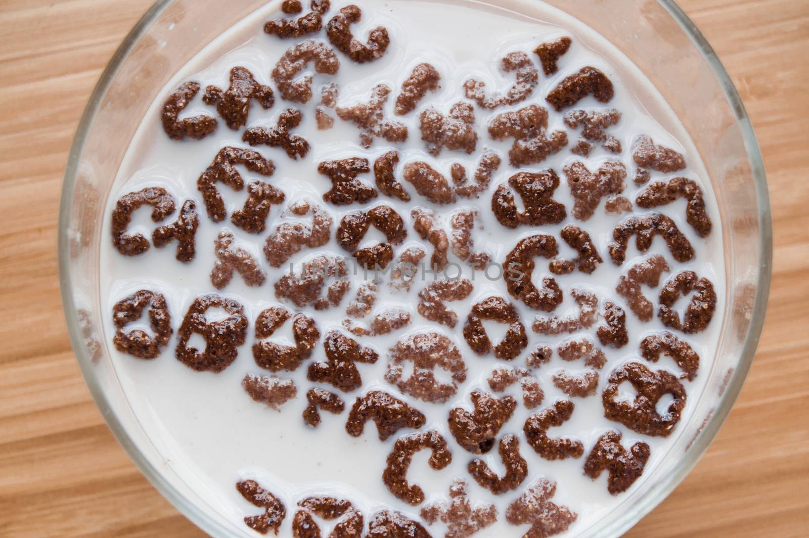 Top view of milk bowl, alphabet letters of cereal and chocolate flakes on wooden table, healthy Breakfast for kids and adults, diet and nutrition concept