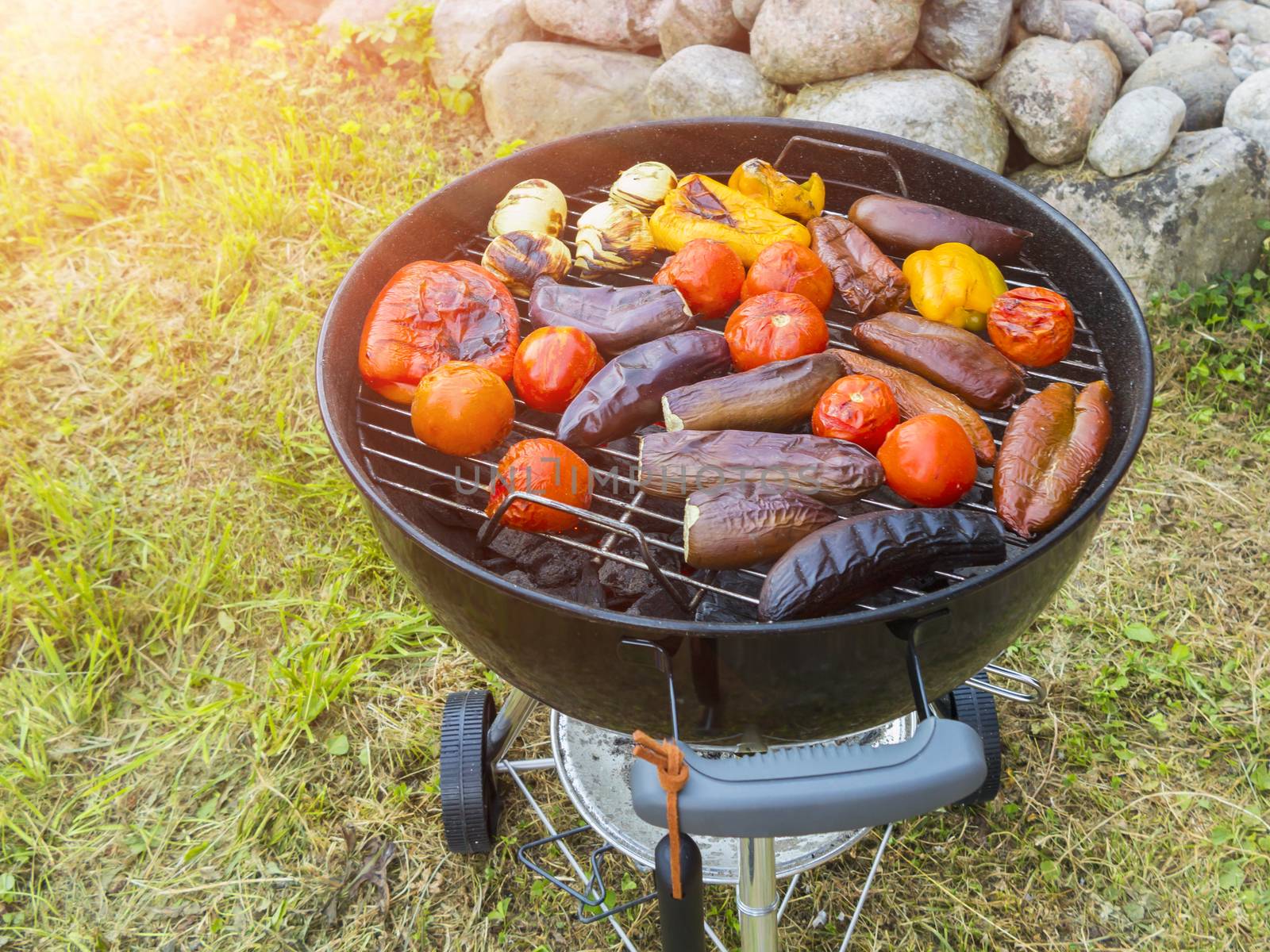 Cooking vegetables on a round grill outdoors in summer by galsand