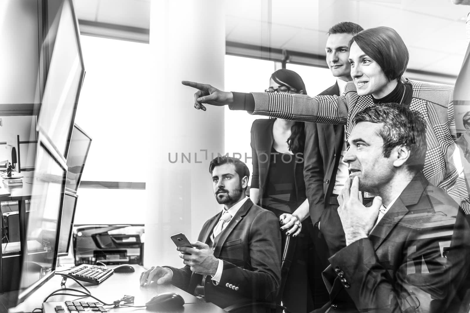 Business people looking at data on multiple computer screens in corporate office. Businesswoman pointing on screen. Business team trading online. Business, entrepreneurship and team work concept.