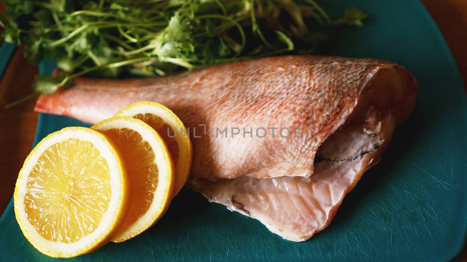 Fresh fish on a cutting board, raw cod fillets with addition of herbs and lemon