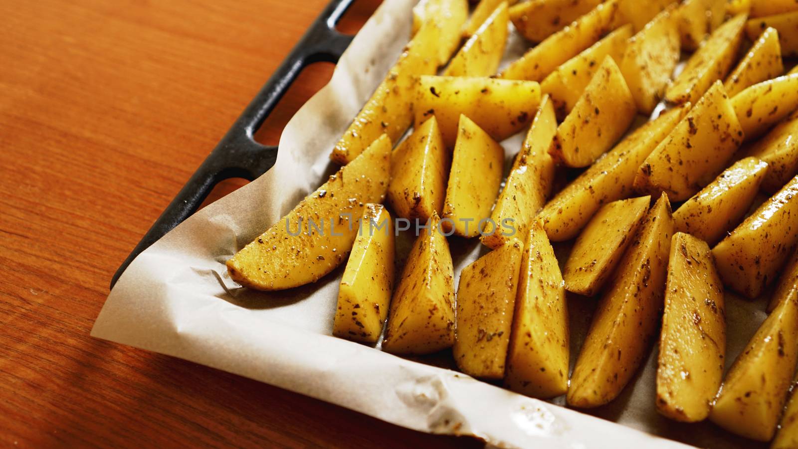 Sliced raw potatoes on a baking sheet with spices and rosemary, top view, copy space