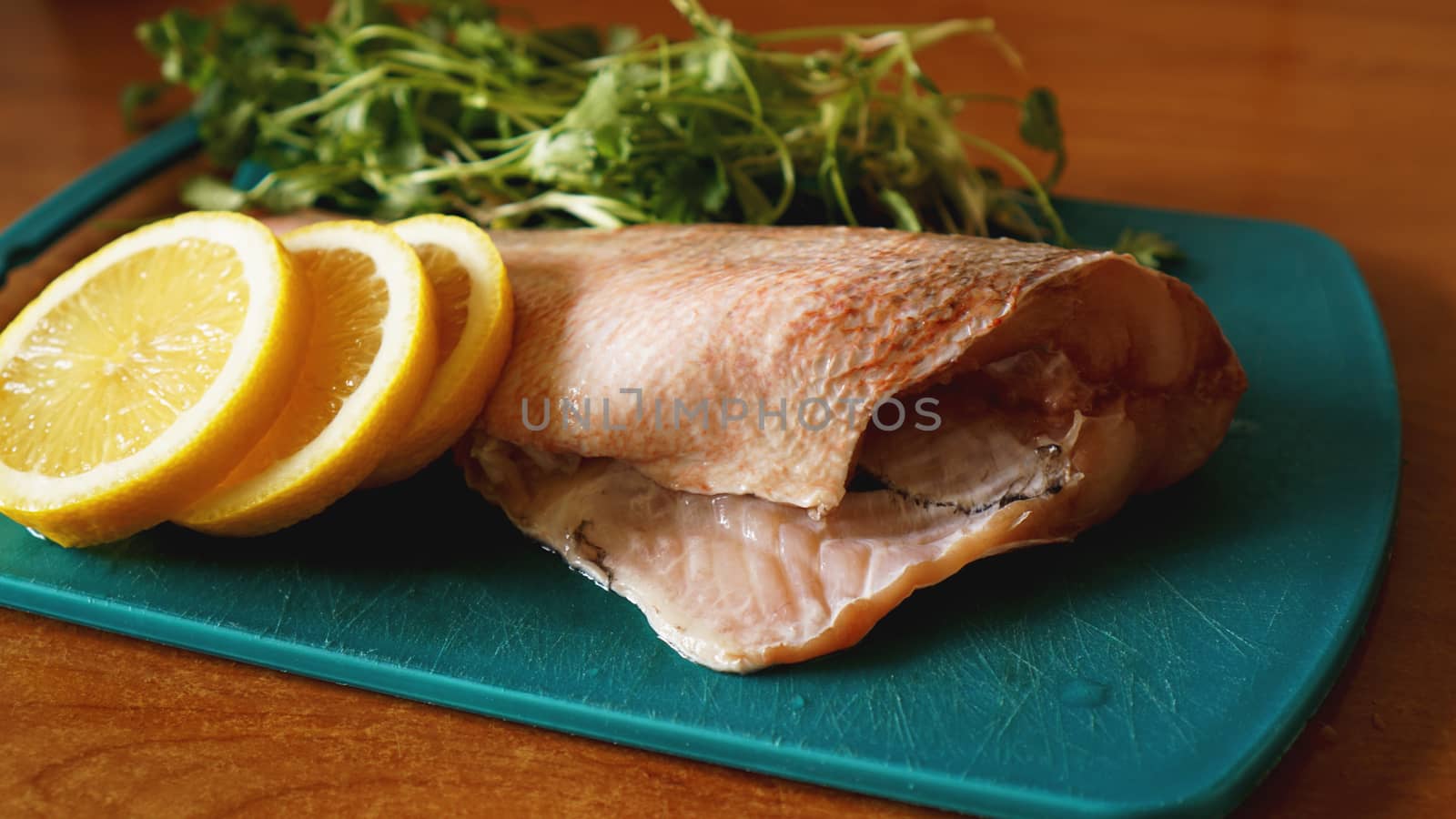 Fresh fish on a cutting board, raw cod fillets with addition of herbs and lemon