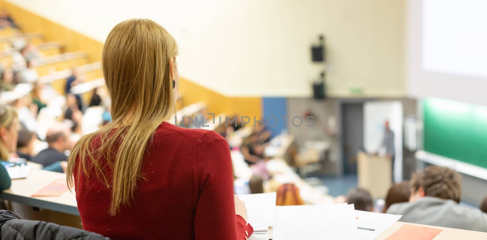 Female student attending faculty lecture workshop making notes. Audience at the lecture hall. Conference and Presentation. Business and entrepreneurship academic education concept.