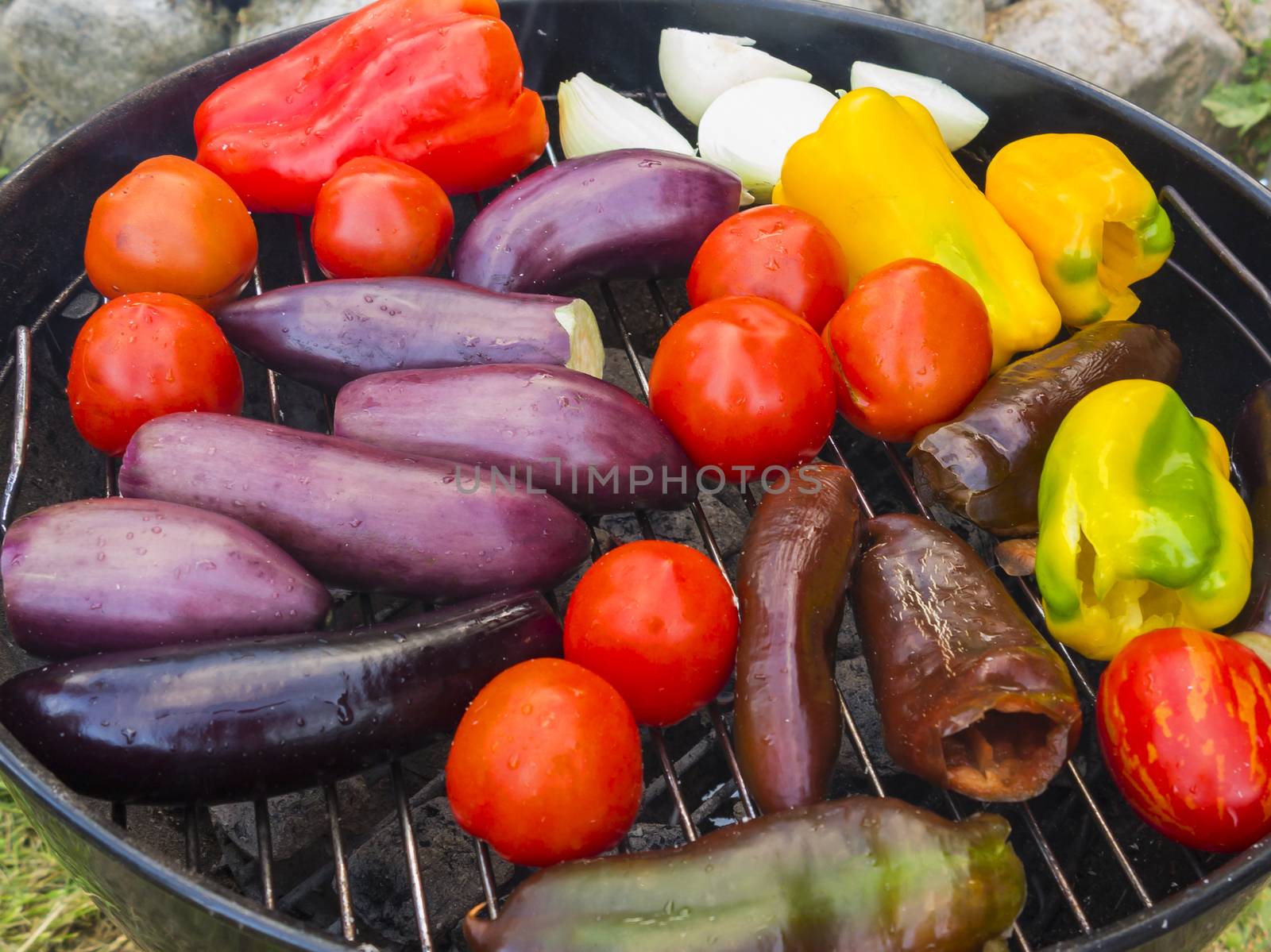 Cooking vegetables on a round grill outdoors in summer by galsand