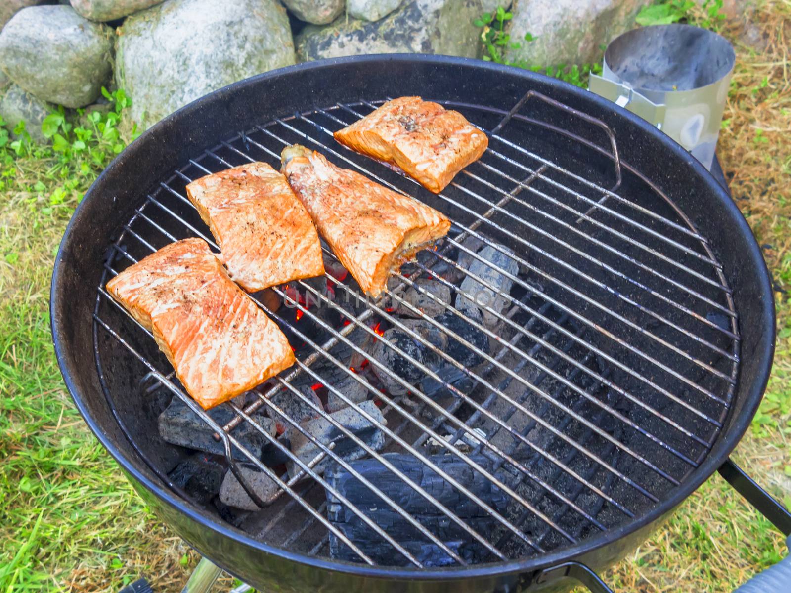 Cooking fresh salmon steaks on the grill, outdoors in summer by galsand