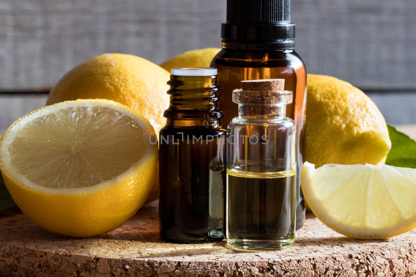 Bottles of lemon essential oil with lemons in the background