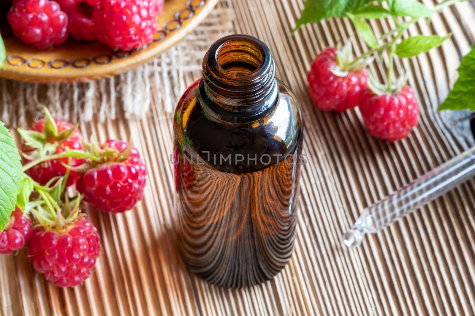 A bottle of raspberry seed oil with fresh fruit