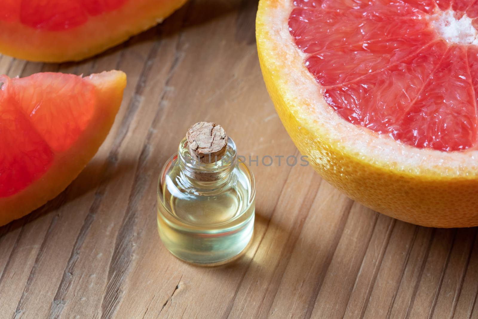 A bottle of grapefruit essential oil with fresh grapefruit by madeleine_steinbach
