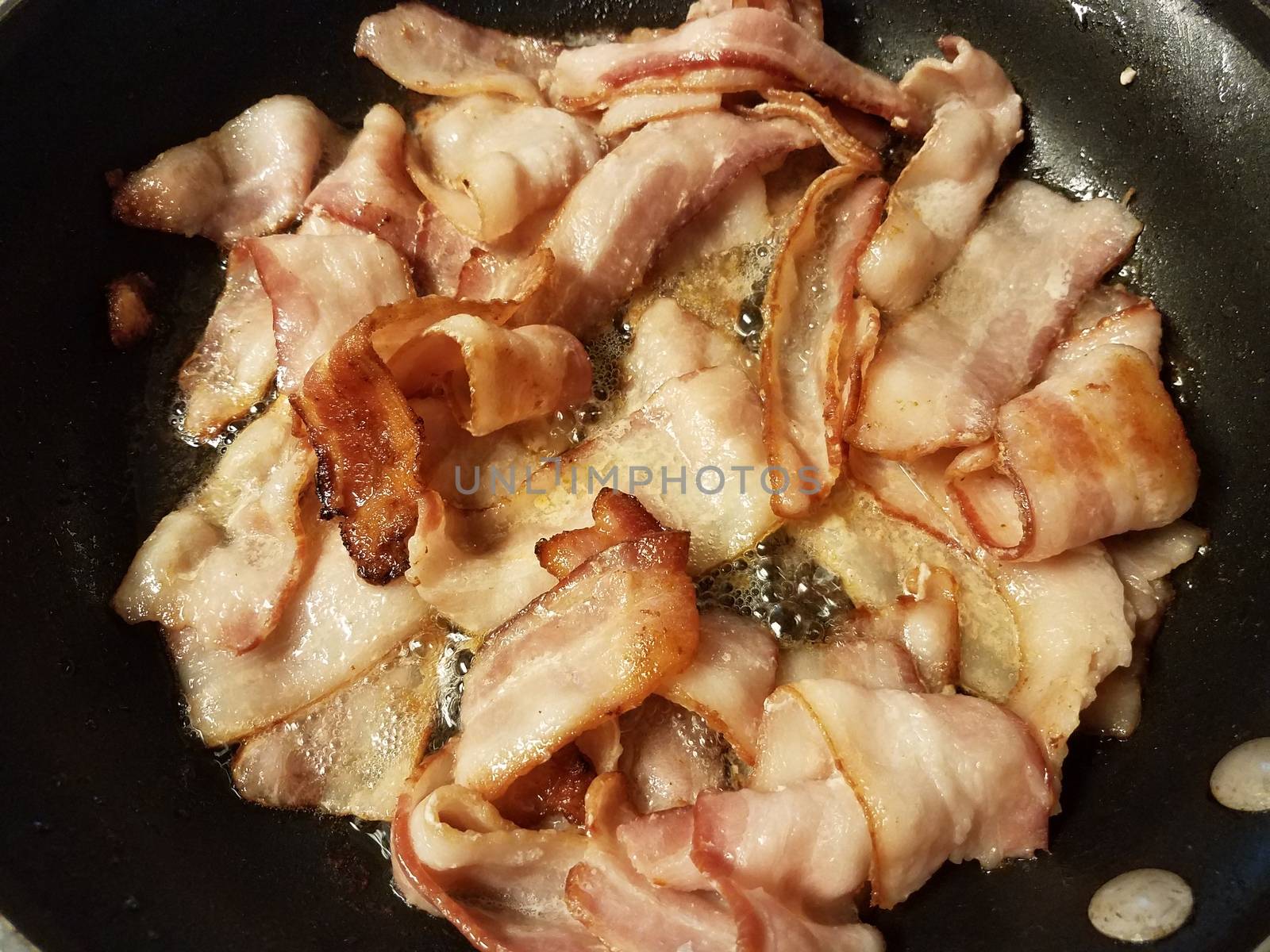 bacon cooking in frying pan or skillet on stove by stockphotofan1