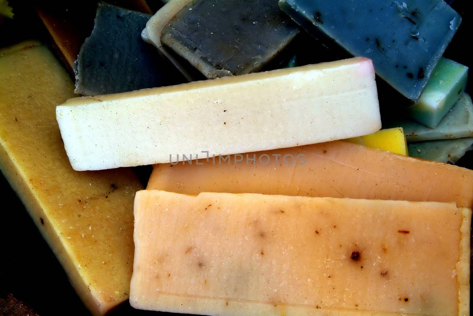 Quadrangular pieces of soap of various colors displayed on newsprint paper grouped by colors: brown-white-red-orange-yellow-green.