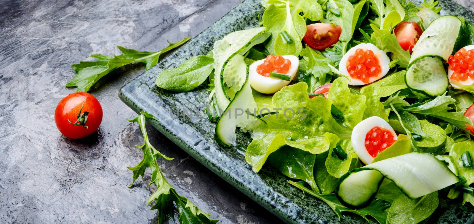 Spring vegetable salad with greens, cucumber, egg and red caviar